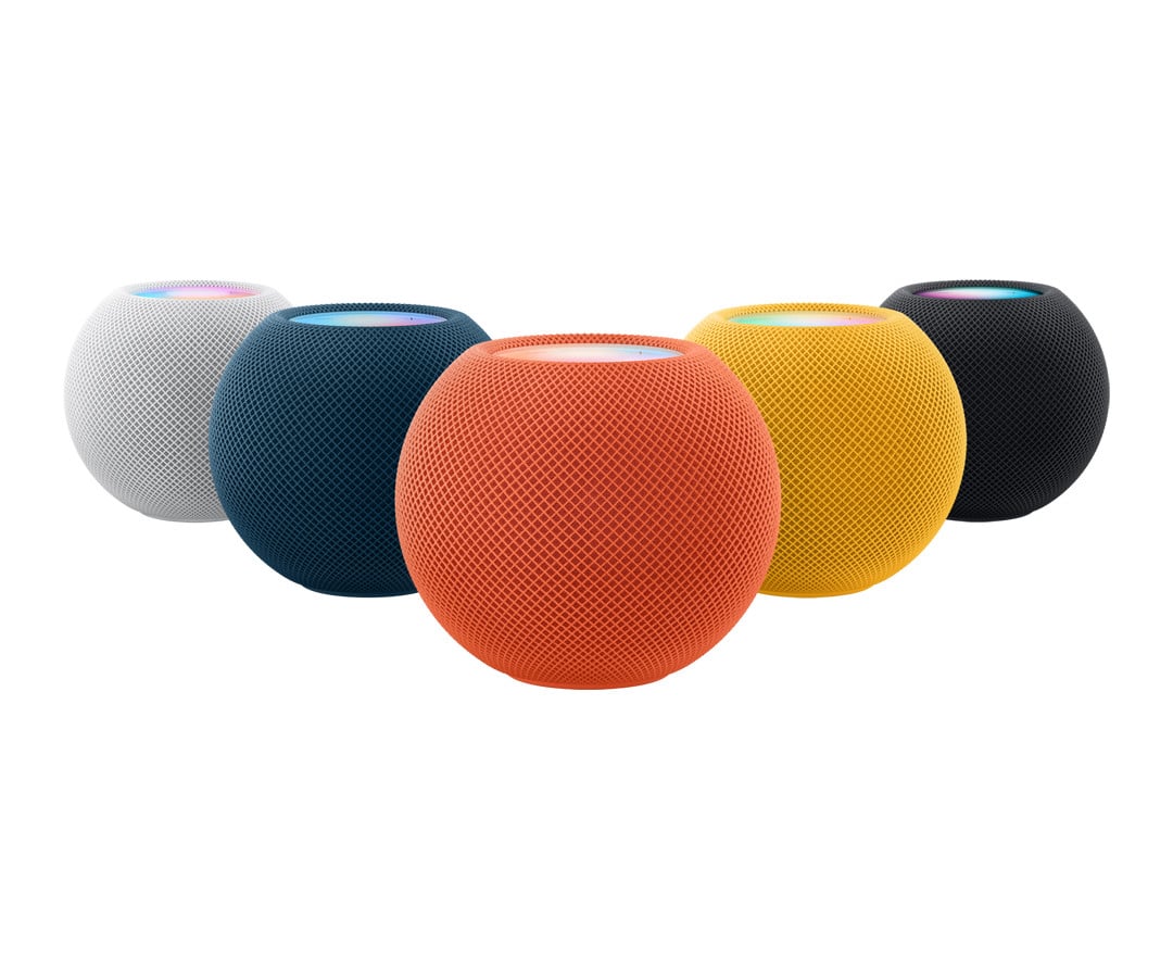 Fem HomePod mini-högtalare i färgerna vit, blå, orange, gul och svart på rad, med rund, nätbelagd design.