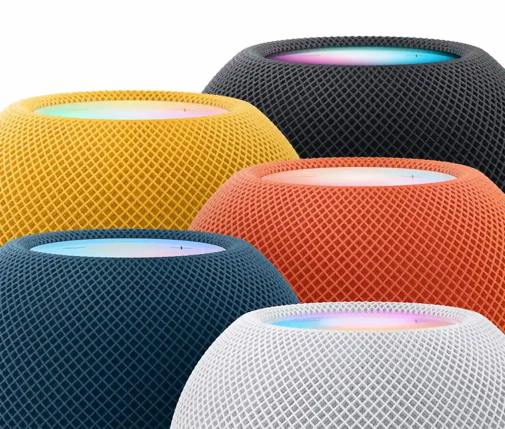Närbild av fem HomePod mini-högtalare i färgerna midnatt, gul, orange, blå och vit med lysande touchytor.