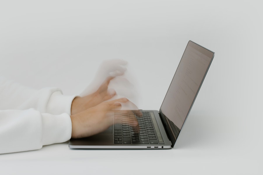 coding - hands type in a blur on a laptop keyboard