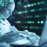 AN android robot working at a laptop
