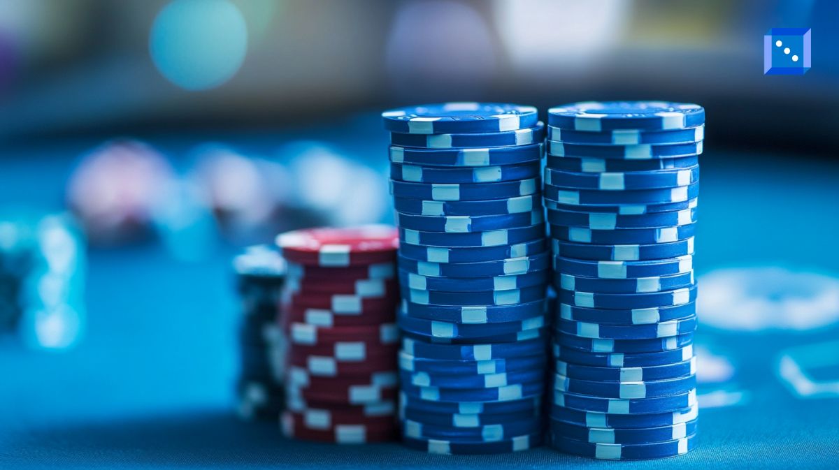Stacks of blue and red poker chips on a casino table with a blurred background, evoking the high-stakes excitement of gambling. The close-up shot highlights the neatly stacked chips, representing wealth, strategy, and risk in poker or casino games.