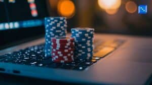 Stacks of red and blue poker chips placed on a laptop keyboard, symbolizing online casino gaming, with a blurred background of warm glowing lights.