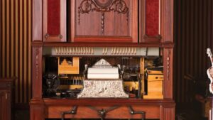 A vintage mechanical music machine with ornate details, showcasing its inner mechanics and a roll of paper ready to play.