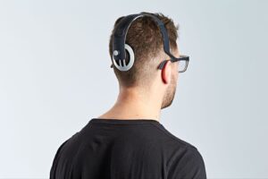 A person with short hair, wearing glasses and a black shirt, faces away. He have futuristic Gennaris Bionic Eye on, creating a modern, tech-savvy feel.