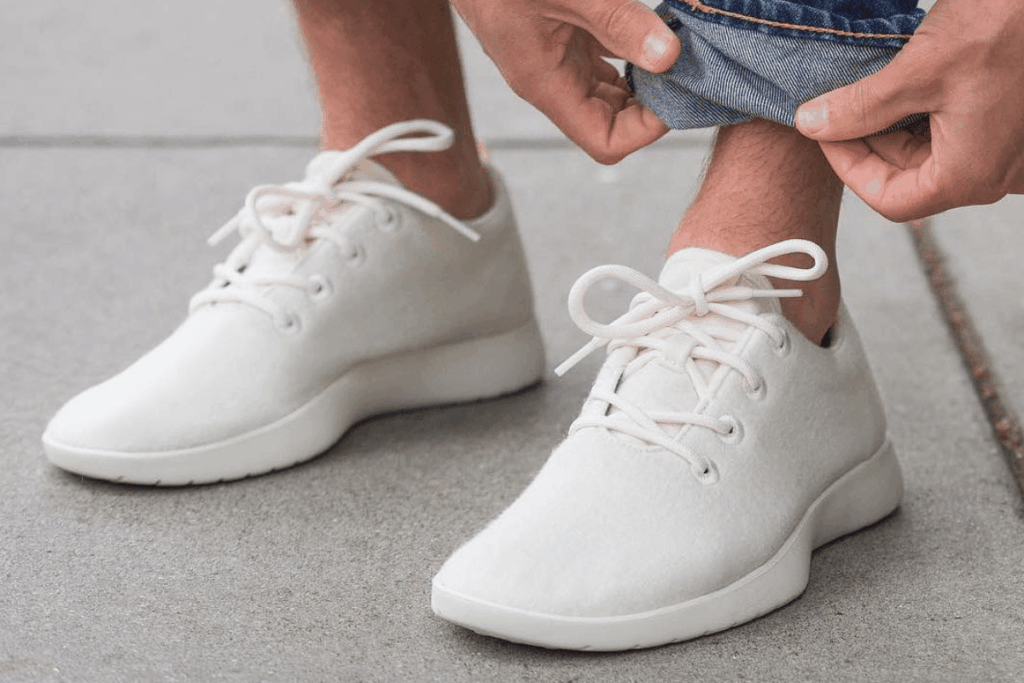 Man wearing white Allbirds sneakers tying laces on casual shoes outdoors close-up sustainable wool footwear minimalist style. Allbirds AI Pivot Runs Into Limits Of Capital And Experience