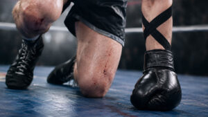 Fallen boxer with wraps forming a black X on his forearm.